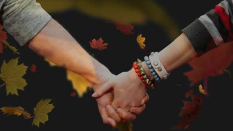 pareja cogida de la mano contra las hojas de otoño voladoras 4k