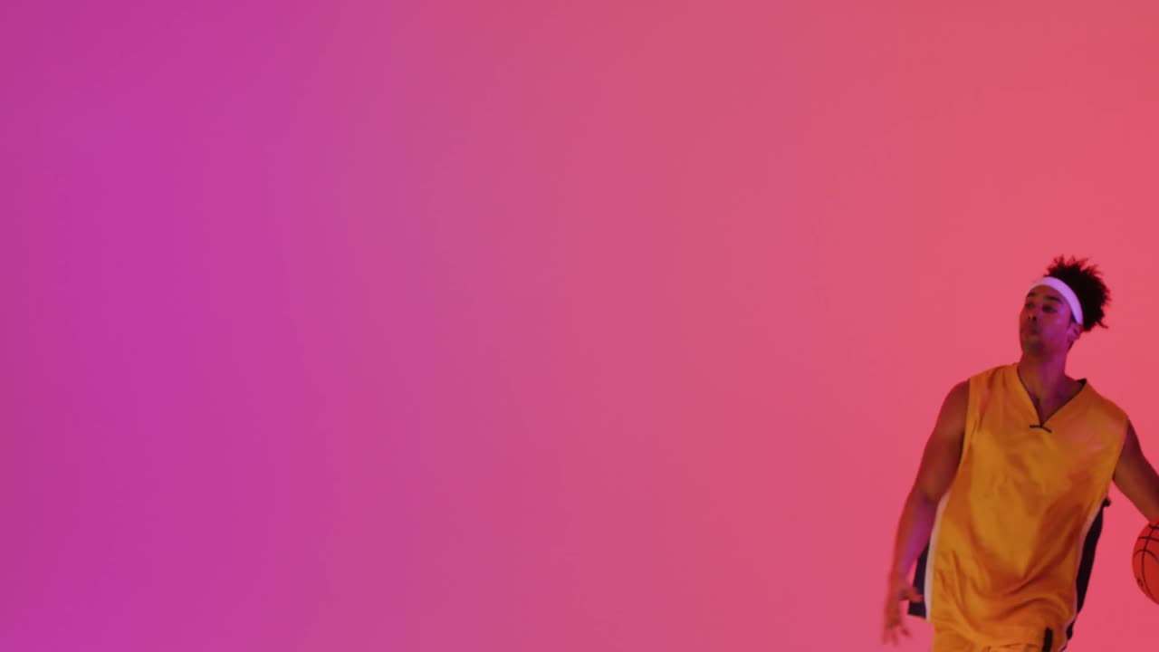 Video of biracial male basketball player throwing ball on orange to pink background