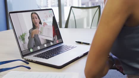 video de una mujer biracial haciendo una videollamada en un portátil con una compañera de trabajo biracial