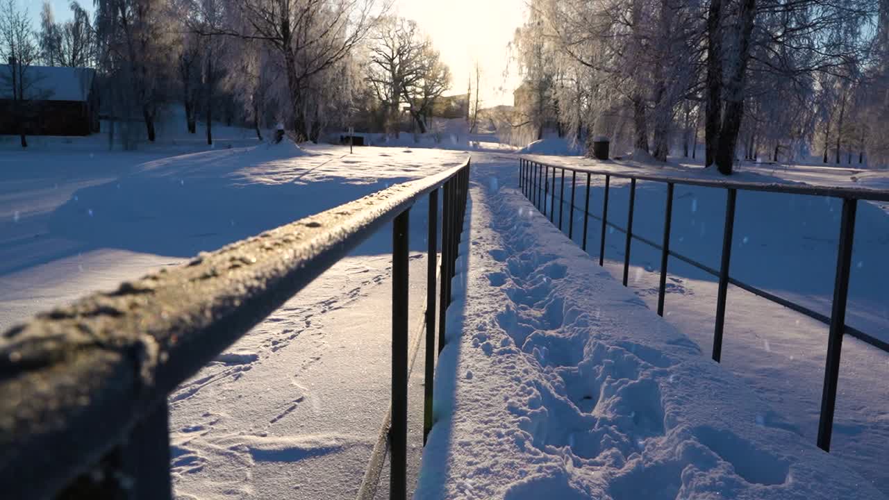 profundas huellas de pies en la nieve sobre un viejo puente de acero, majestuosa puesta de sol de invierno y nevadas