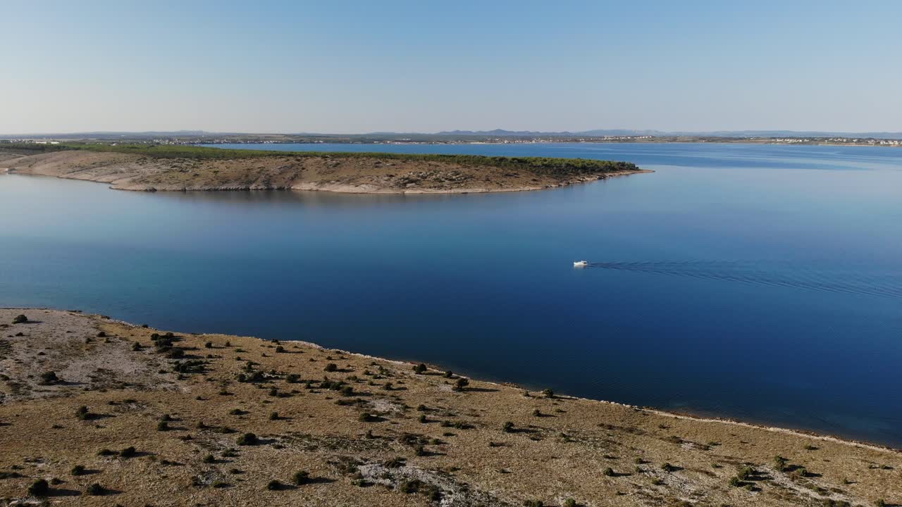 Aerial view on a small white boat on blue waters camera is moving forward