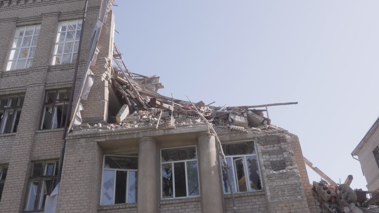 Panning shot of missile strike aftermath on school building with collapsed second story