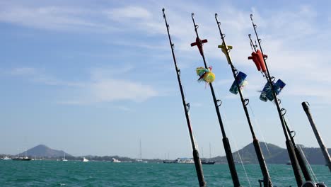 las varas de pesca se balancean suavemente en un barco en phuket, tailandia, bajo un cielo despejado, capturando una escena marítima serena