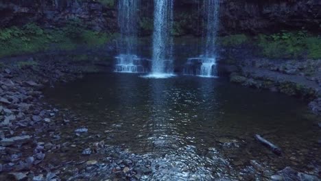 drone volando hacia atrás para revelar una cascada en gales