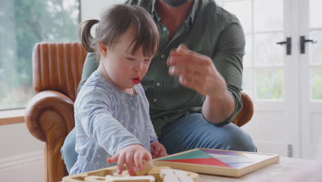 Padre-Con-Hija-Con-Síndrome-De-Down-Jugando-Con-Formas-De-Madera-En-Casa-Juntos