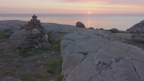 Rock-stack-balancing-on-the-top-of-a-cliff-overlooking-the-calm-ocean-with-a-beautiful-golden-sunset-in-the-Scottish-highlands