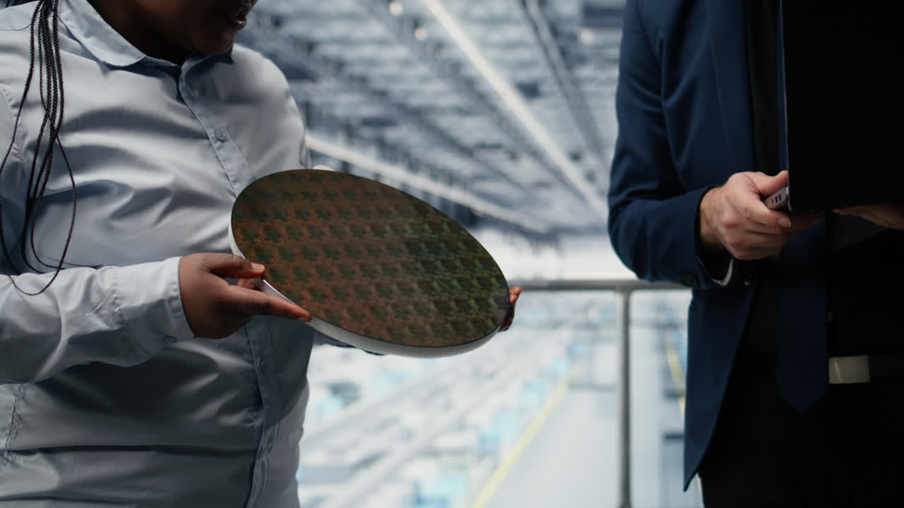 Lavoratori in una fabbrica intelligente di microchip che esaminano il design del substrato semiconduttore