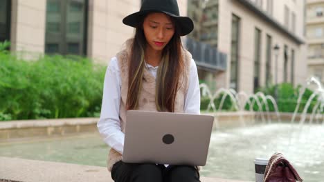 hispanic woman browsing laptop on street