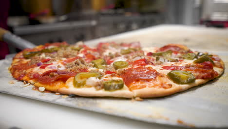 el chef de la pizzería corta pizza caliente recién horneada con un cortador de pizza mezzaluna de acero inoxidable, 4k