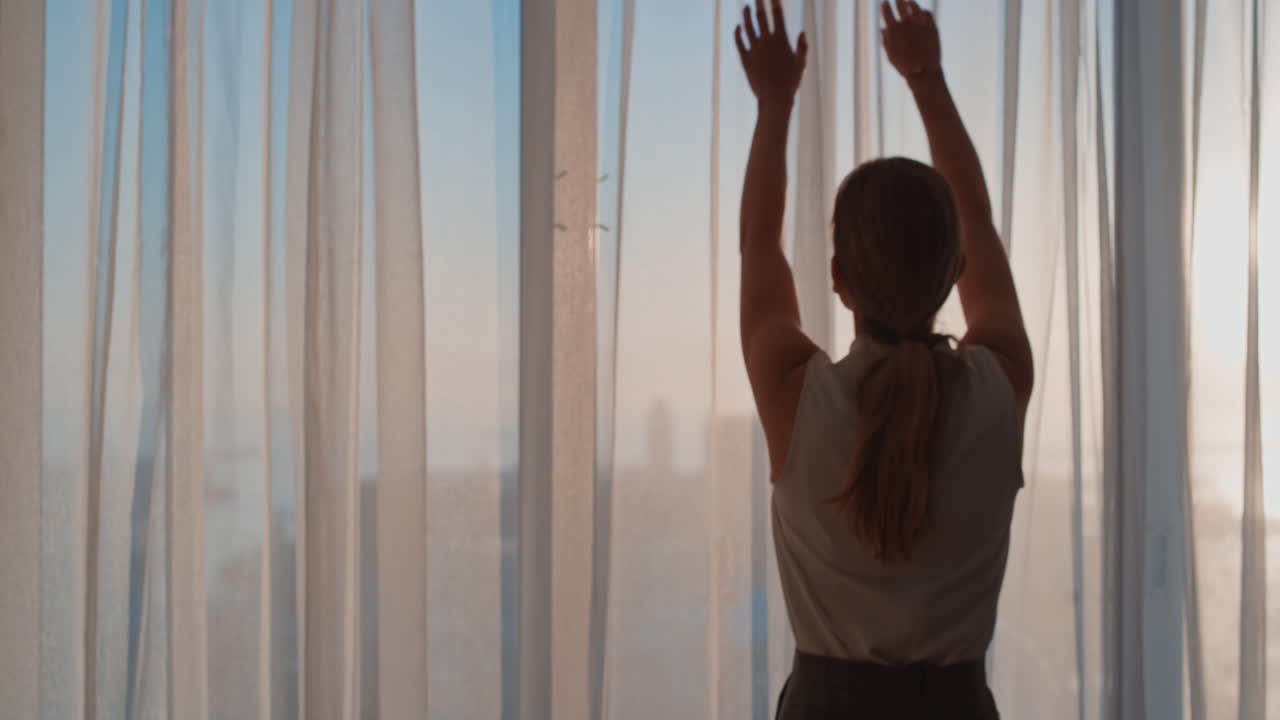 mujer de negocios abriendo cortinas en la habitación del hotel mirando por la ventana al fresco nuevo día exitosa mujer independiente planeando adelante al amanecer