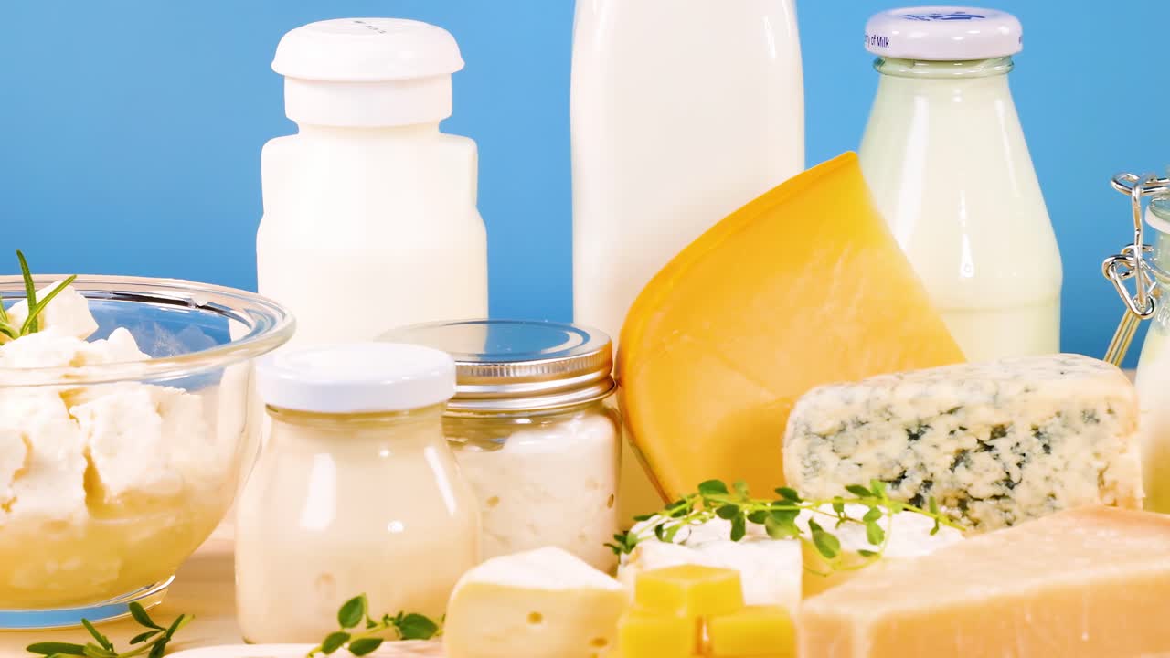 A selection of cheeses and dairy products arranged against a vibrant blue backdrop.