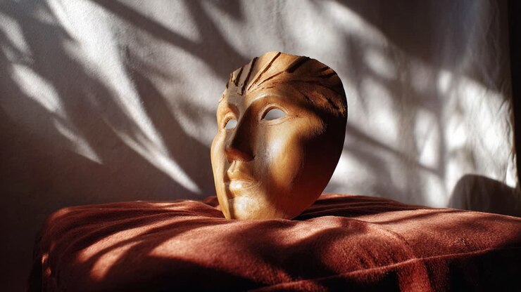 Raffigurazione artistica di una maschera di argilla appoggiata elegantemente su una superficie di tessuto morbido, illuminata da una luce naturale soffusa con ombre che creano un'atmosfera unica