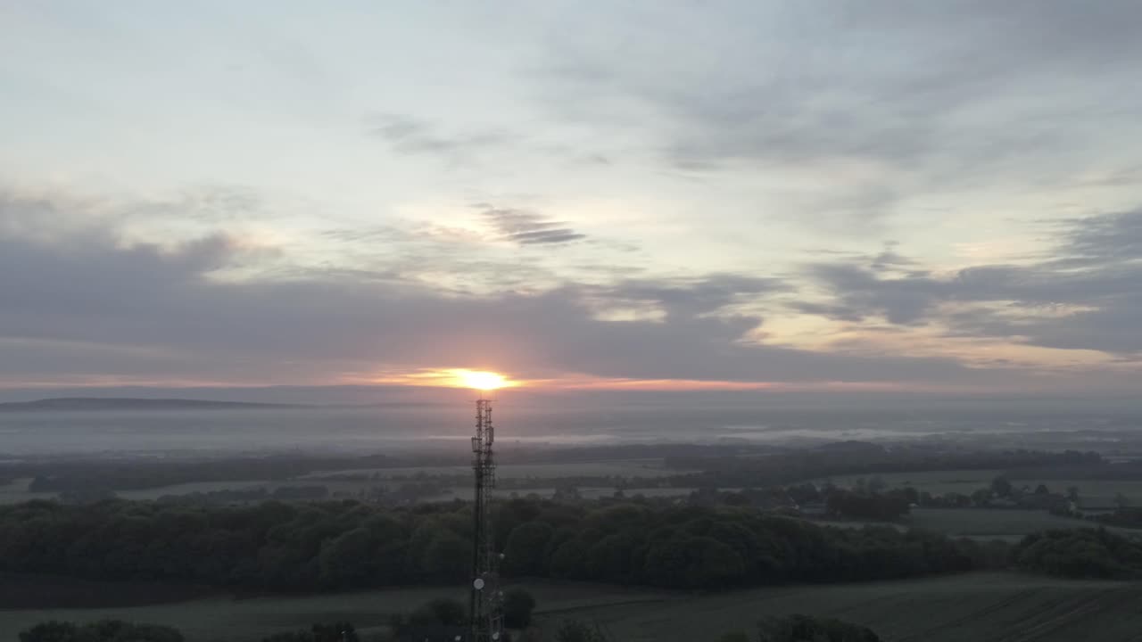 Early sunrise aerial lowering down telecom towers on agricultural rural farmland countryside