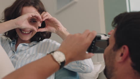 pareja feliz tomando fotos juntos usando la cámara divirtiéndose en casa en el sofá jugando disfrutando de una relación romántica