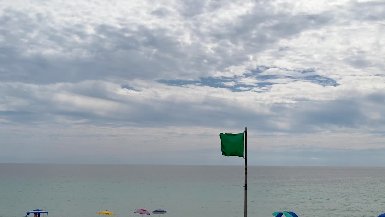 bandera verde volando sobre las aguas claras de la costa del golfo en la playa de arena blanca