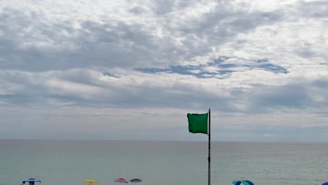 Grüne-Flagge-Weht-über-Dem-Klaren-Wasser-Der-Golfküste-Am-Weißen-Sandstrand