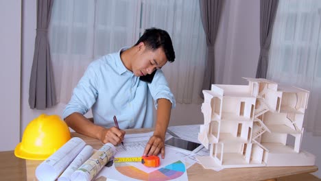 young architect talking on phone and working with blueprints