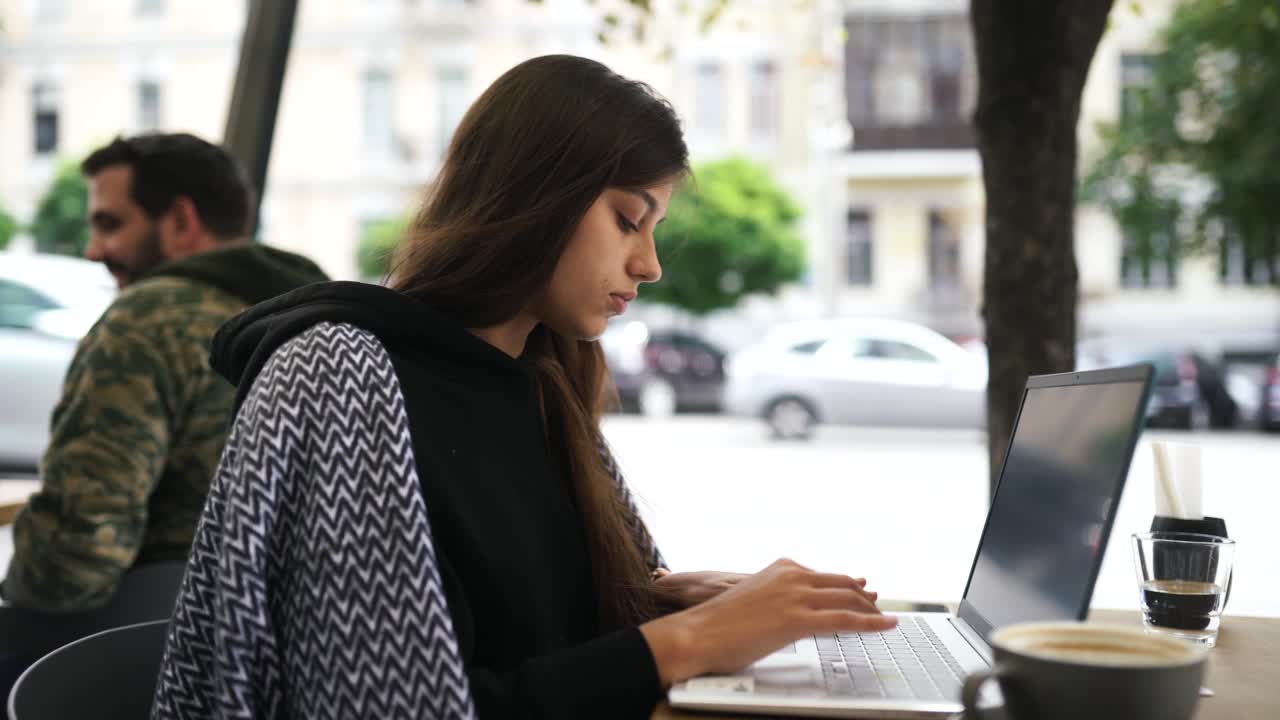 mujer joven trabajando en una computadora portátil en un café