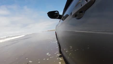 coche gris conduciendo a la orilla del mar