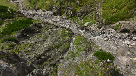 descending drone shot of rocky dried up river running from mountaintop in midst of austrian alps mountain range