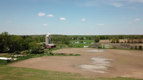 Aerial-view-of-agricultural-fields-and-a-classic-red-barn-with-silo