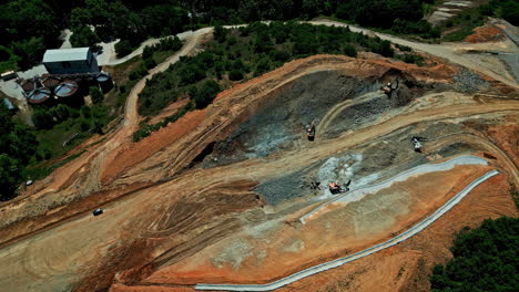 aerial orbit, large construction site with small excavators digging brown earth