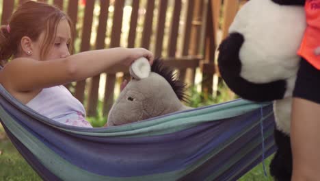 jóvenes niñas felices en el campamento de verano acostadas en hamacas coloridas relajándose jugando afuera con peluches muñecas de perro en el campo de hierba verde niños niños en cámara lenta