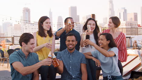 Friends-Gathered-On-Rooftop-Terrace-For-Party-With-City-Skyline-In-Background-Making-Toast-With-Drinks