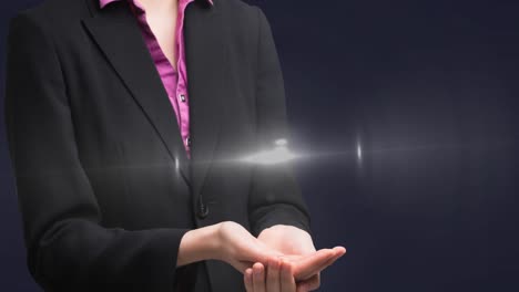 animation of glowing spot of light over businesswoman hands on grey background