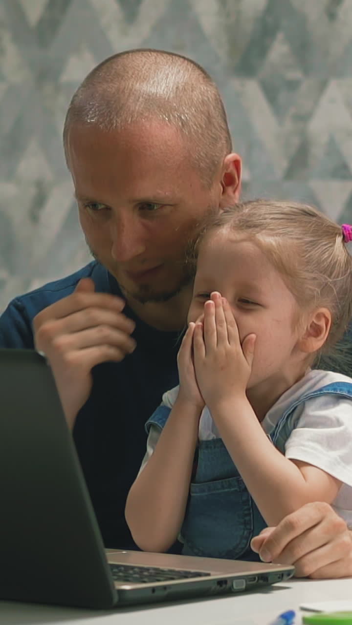 closeup slow motion little daughter in blue sundress at pope's lap, staring with bald father in computer screen, surprised, frightened, cover face with his palm, then sad, beats himself on forehead