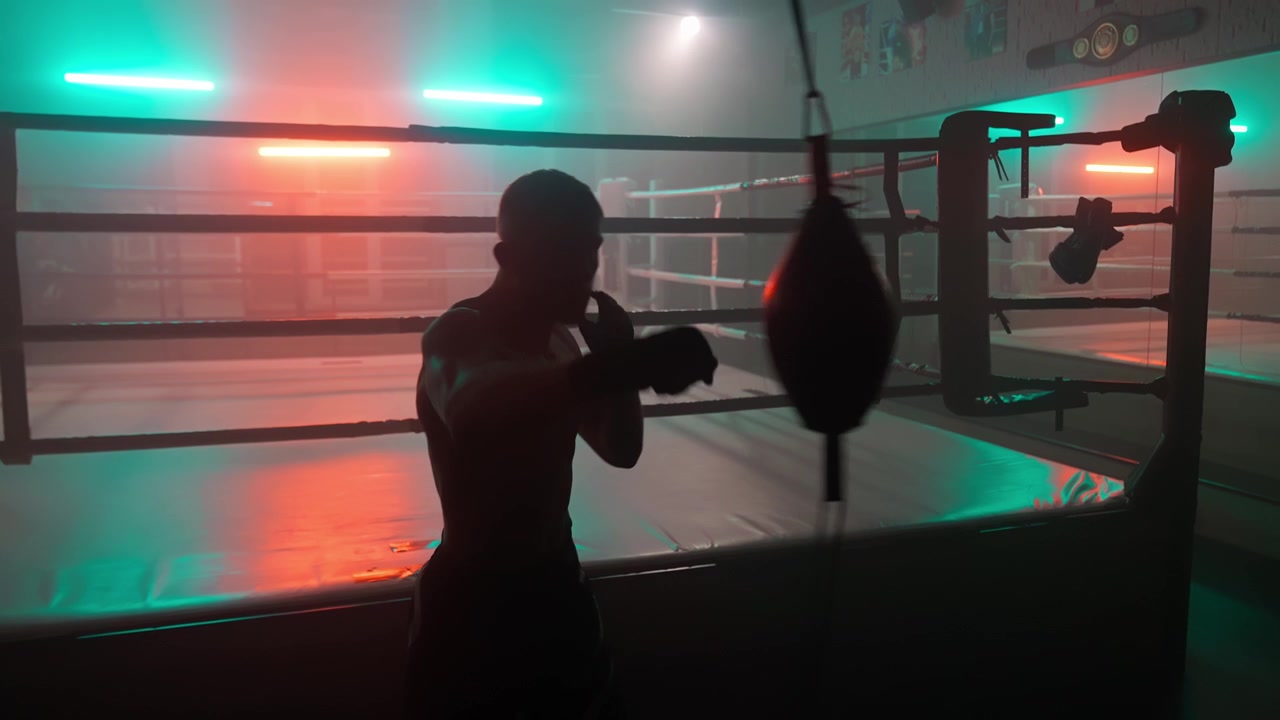 Silhouette eines Boxers beim Training mit einem Speedbag in einem dunklen Fitnessstudio mit Neonlichtern