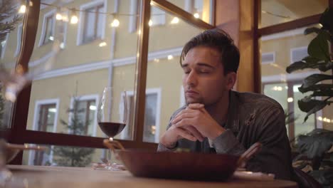 portrait of a handsome bearded sad guy waiting for dinner in a cafe or restaurant.