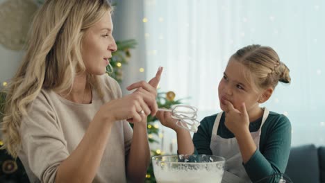 caucasian mother and daughter preparing baking using electric mixer and later tasting.