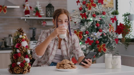 retrato de niños sentados en una mesa en una cocina decorada con navidad navegando por las redes sociales