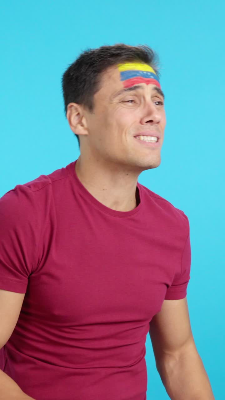 Nervous man cheering for Venezuela during a match looking away