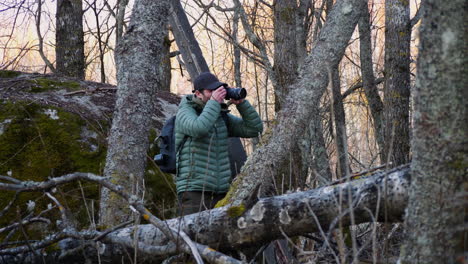 male photographer is hiking in the woods taking a photo