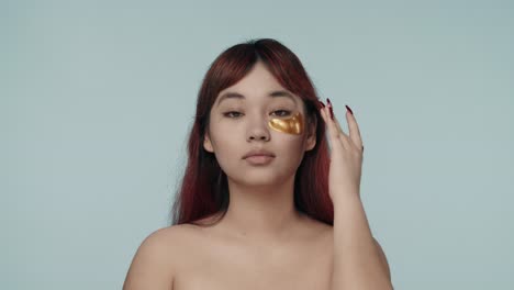 woman applying gold eye patches