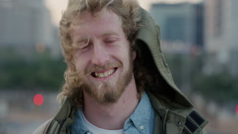 Retrato-Feliz-Joven-Sonriendo-Disfrutando-De-Un-Estilo-De-Vida-Urbano-Relajado-Barbudo-Hipster-Hombre-Viento-Soplando-Cabello-Luciendo-Alegre-En-La-Ciudad-Al-Atardecer-Seguro-Exitoso