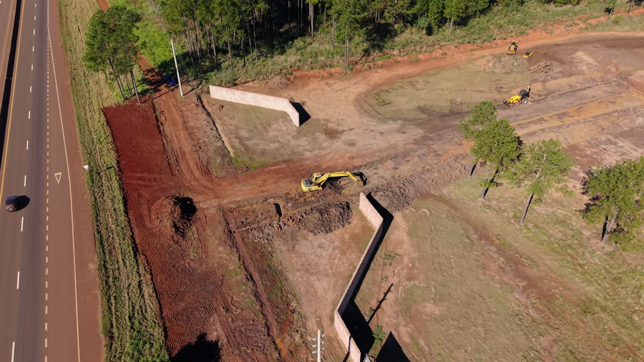 Aerial view of machinery working on a roadside excavation in a suburban infrastructure site.