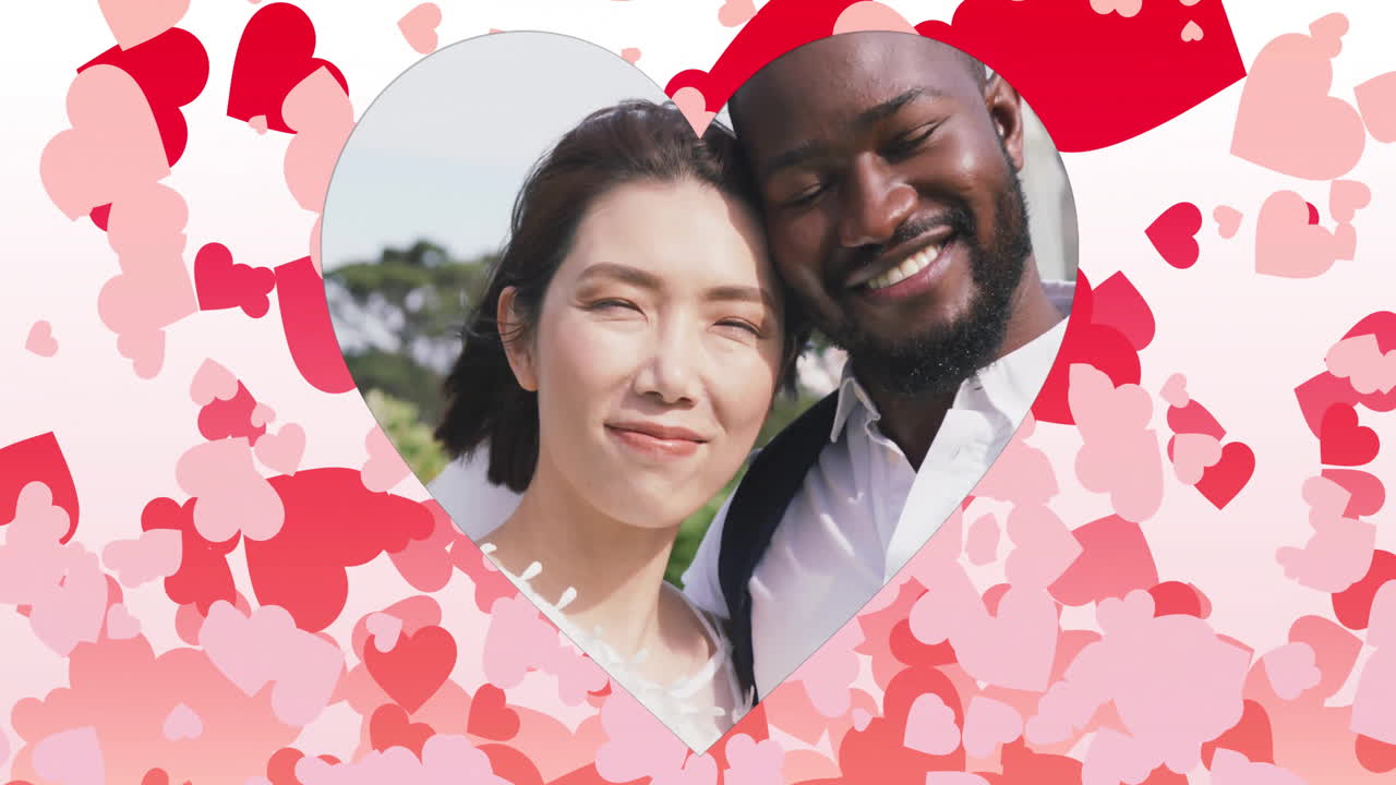 웃는 커플이 야외에서 심장 모양의 애니메이션이 그들을 둘러싸고 떠다니고 있습니다.