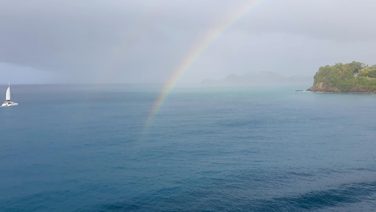세일보트 가 왼쪽 에서 들어오는 것 처럼 물 위 에 있는 이중 무지개 의 전망