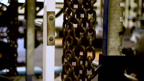 panning rack focus shot of a weight plate to a set of chains in a weight room