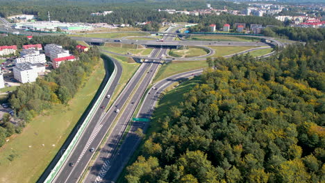 Aerial-view-of-a-complex-highway-interchange-with-multiple-overpasses-and-lanes,-surrounded-by-urban-structures-like-buildings