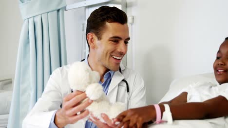 el médico entretiene a un niño enfermo con un oso de peluche.