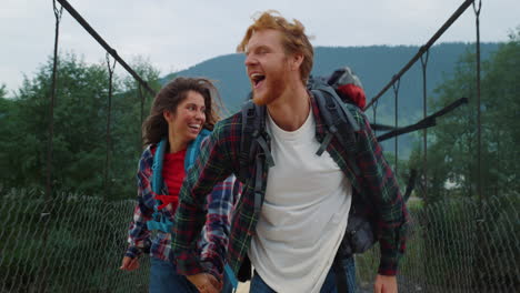 travelers running nature mountains on river bridge. happy couple holding hands.