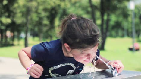 little girl washes her face and drink cool water from a drinking fountain, on a hot summer day