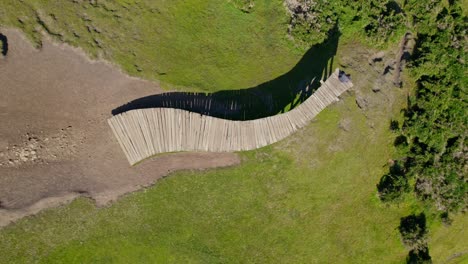 Rotating-overhead-view-of-the-Muelle-de-las-Almas-with-a-person-sitting-meditating-in-solitude,-Cucao-Chiloe,-Chile