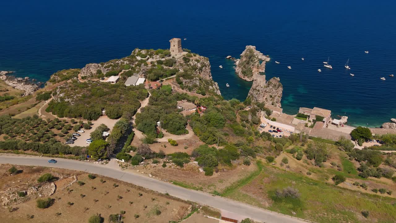 Push in aerial drone shot of Tonnara di Scopello (Sicily, Italy) from the town, showcasing historic architecture and scenic summer atmosphere