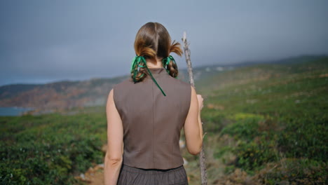 independent hiker walking path in solitude rear view. summer girl strolling hill