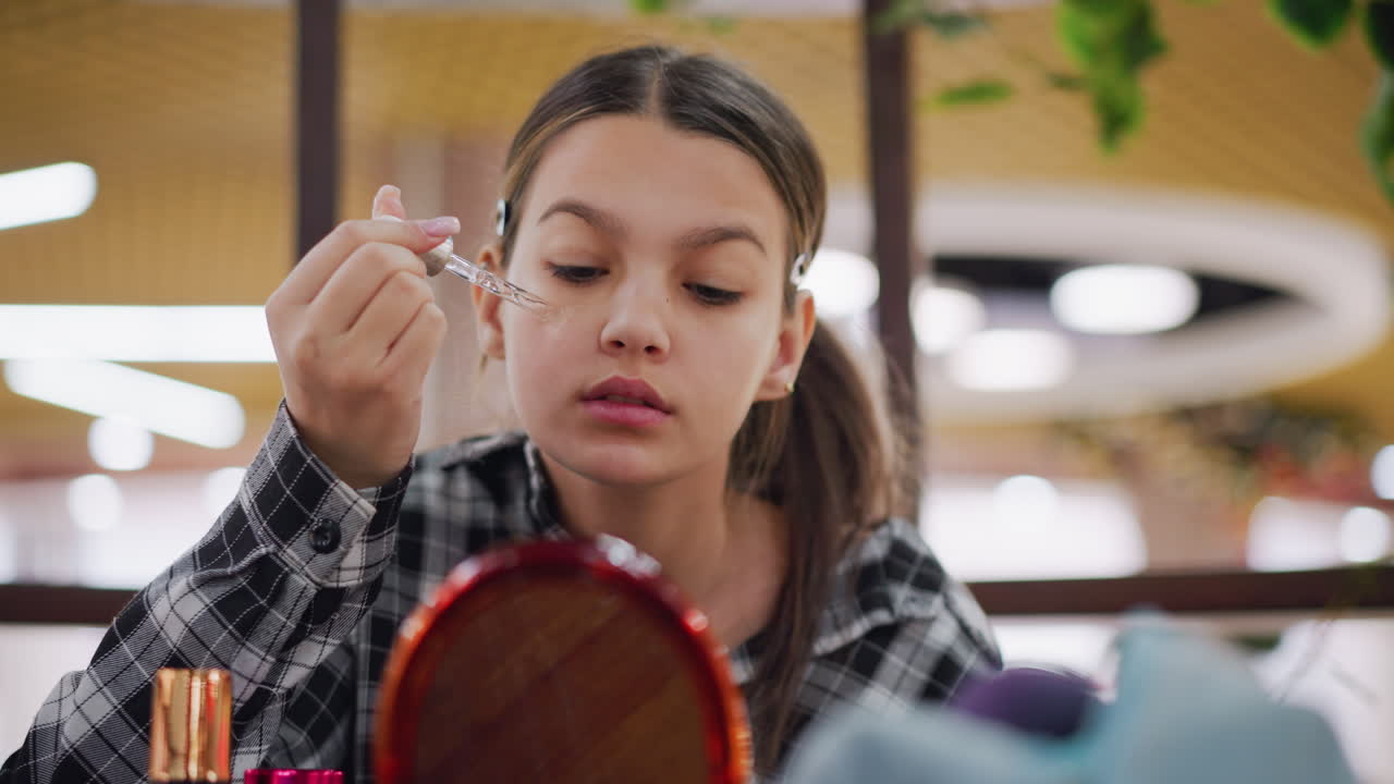 la joven aplica cuidadosamente el suero a la cara mientras se maquilla, centrándose en la rutina de cuidado de la piel, se mira en el espejo con concentración, asegurando una aplicación uniforme para una piel lisa y radiante